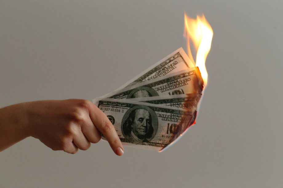 Notas de cem dólares pegando fogo simbolizando o desperdício de dinheiro ao continuar pagando conta de luz
