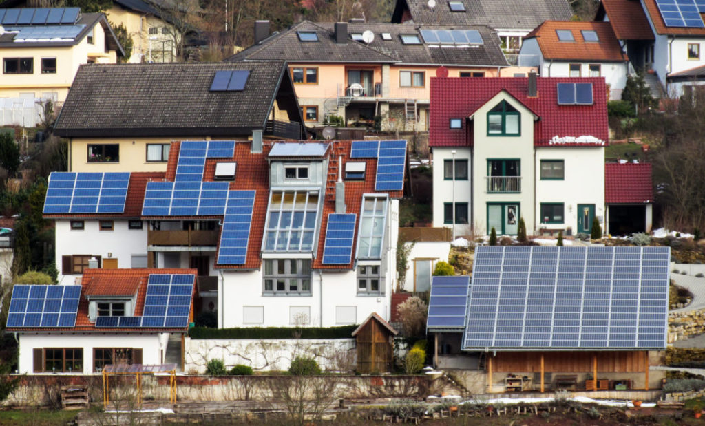 diversos paineis solares nos telhados de várias casas em um bairro de estilo germanico.